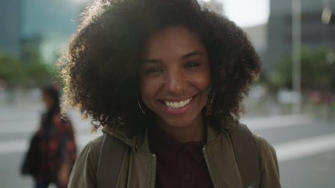 portrait of beautiful trendy african american woman smiling at camera looking confident running hand through hair enjoying urban city lifestyle real people series