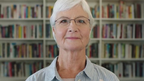close up portrait of elegant middle aged woman teacher smiling happy looking at camera elderly lady wearing glasses in library experience knowledge