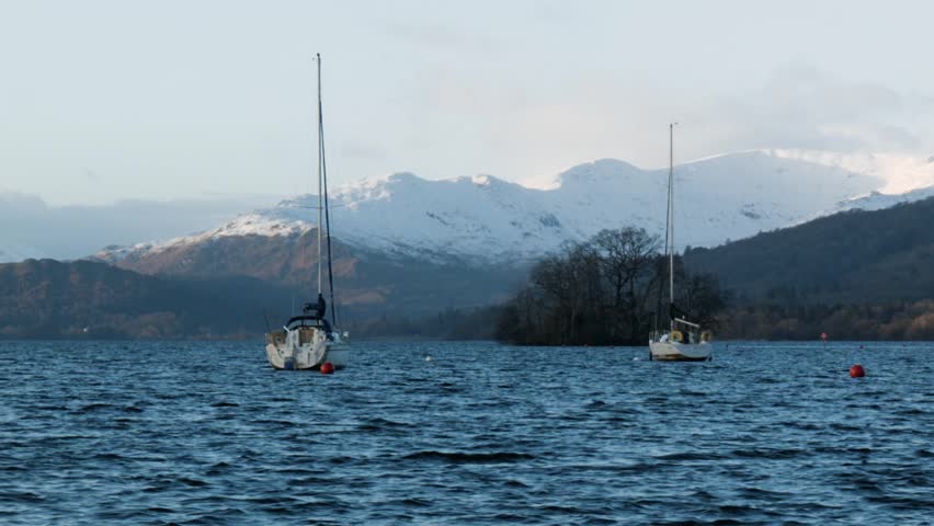 Two boats on Lake Windemere with snowy peaks in the distance. 