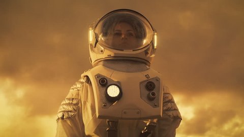 Low Angle Shot of Female Astronaut in the Space Suit Looking Around Alien Planet. Red and Orange Planet Similar to Mars. Advanced Technologies, Space Travel, Colonization Concept.  RED EPIC-W 8K.