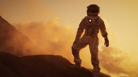 Silhouette of the Astronaut Standing on the Rocky Mountain of the Alien Red Planet/ Mars. First Manned Mission on Mars. Space Exploration, Colonization. Shot on RED EPIC-W 8K Helium Cinema Camera.