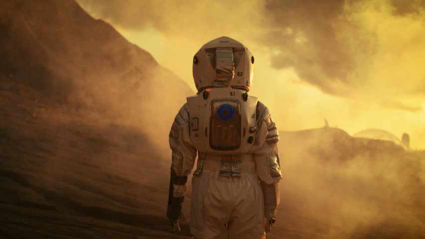 Following Shot of Female Astronaut in Space Suit Confidently Walking on Mars, Turing Around and Looking into the Camera. Red Planet Covered in Gas and Smoke. Shot on RED EPIC-W 8K Helium Cinema Camera Royalty-Free Stock Footage #1008373372