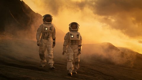 Two Astronauts in Space Suits Confidently Walking on Mars, Exploration Expedition on the Planet's Surface. Space Travel, Planet Discovery, Colonization Concept. Shot on RED EPIC-W 8K Helium Camera.