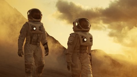 Two Astronauts in Space Suits Confidently Walking on Mars, Exploration Expedition on the Planet's Surface. Red Planet Covered in Rocks, Gas and Smoke. Humans Overcoming Difficulties. 4K UHD.