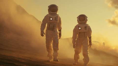 Two Astronauts in Space Suits Confidently Walking on Mars, Exploration Expedition on the Planet's Surface. Red Planet Covered in Rocks, Gas and Smoke. Humans Overcoming Difficulties. 4K UHD,