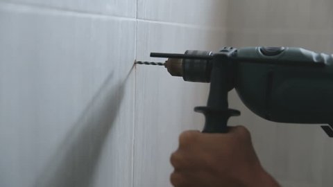 Close up of hand professional young repairman fixing something in bathroom using drill
