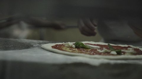An italian "pizzaiolo" is making a pizza margherita in Naples.
