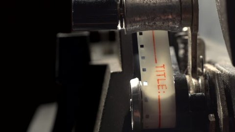 Vintage film leader, then 8mm film, feeds through old projector in macro closeup.