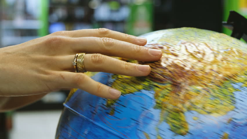 Woman spins the globe in a shop