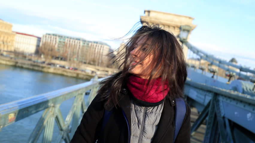 Happy tourist girl walking in city visiting european town on top of a bridge. Woman walking in 120fps slow-motion