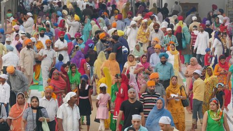 AMRITSAR, INDIA - OCTOBER 2014: Colorfully dressed followers of the Sikh religion walk around the Golden Temple complex in Amritsar, India