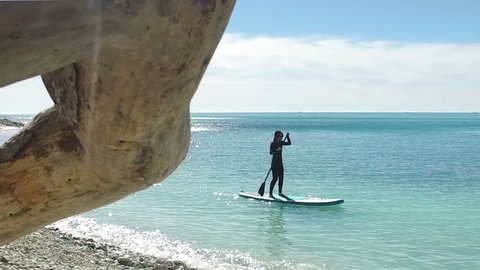 Young Woman Stand Up Paddle Boarding in Blue Sea