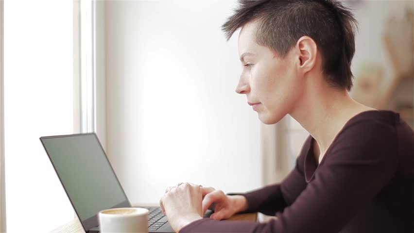 Hipster teenager working on computer laptop at cafe daydreaming looking window pensive look. Young woman types notebook netbook stop to think dream thoughtful look remote work Royalty-Free Stock Footage #1008411844