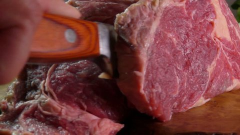 Raw beef steak cut on a wooden board, slow motion