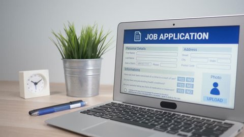 Job application form showing on a laptop computer screen sitting on a desk. Camera is slowly turning around the computer.