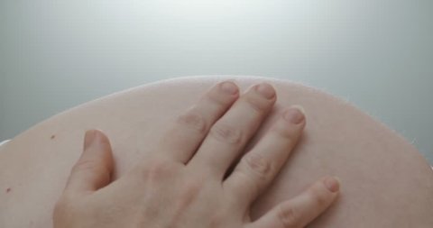 naked belly of a pregnant woman at 30 week stroking hands when the child moves, close-up