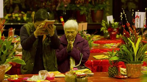 Taipei, Taiwan-10 February, 2016: An older woman and a man are praying and giving offerings in the Dalongdong Baoan Temple in Taipei, Taiwan.