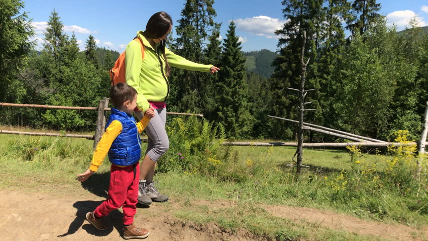 Mother and small son hiking on mountain path
