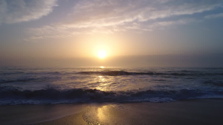 Aerial drone view of beautiful sunrise over the sea. Splashing waves. 