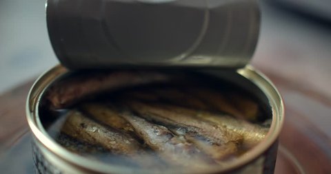Using fork takes a smoked sardines from a tin can