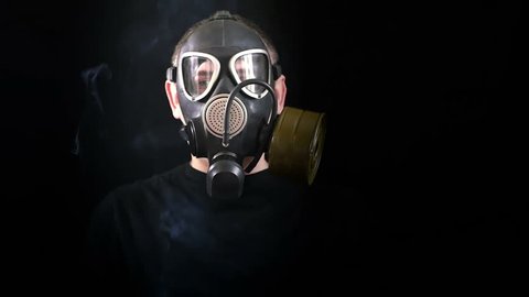 The face of a man in a gas mask on a black background that protects from smoke. Close-up