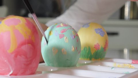Mother and daughter draw Easter eggs with colored paints 4k