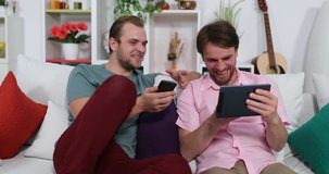 Happy Best Friends Men Watch Funny Movie on Digital Tablet Big Laugh Sit on Sofa