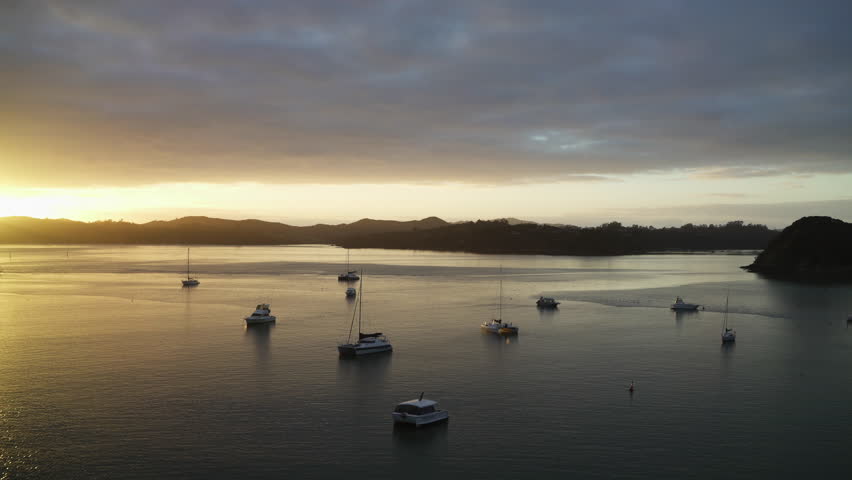 An epic aerial shot of boats floating at sunset with birds flying overhead.