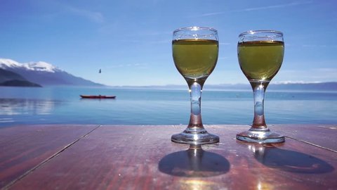 Hand reaching glass with rakija against Ohrid Lake, Macedonia