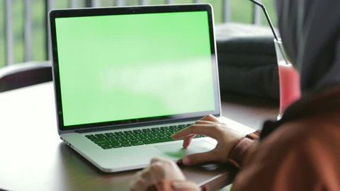 A woman is working in front of laptop / computer at the cafe with green screen