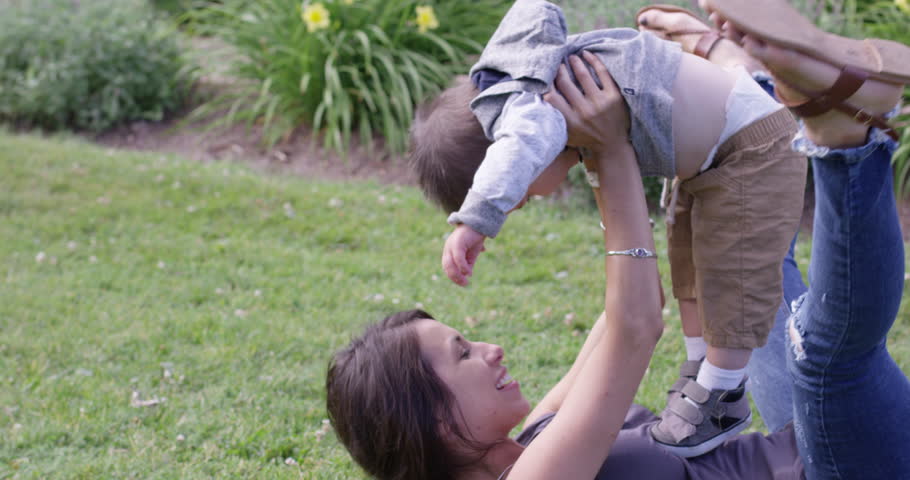 Mother tickling toddler in park - slow motion