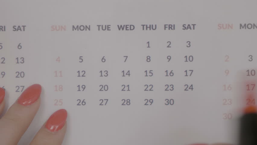 Top view of server woman hands with red nail polish marking days off in calendar with color marker