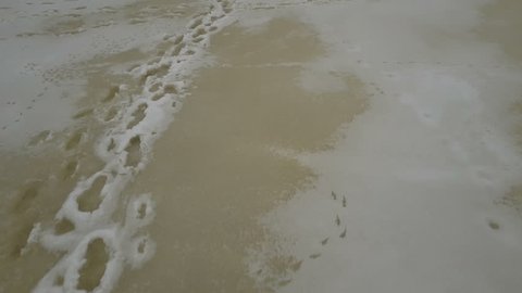 Traces of a person on the ice of a frozen river in winter. Aerial view