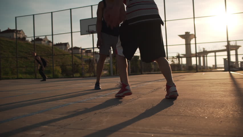 Group of Caucasian males playing streetball dribbling passing having fun. Footage in slowmotion with sun flare | Shutterstock HD Video #1008472978