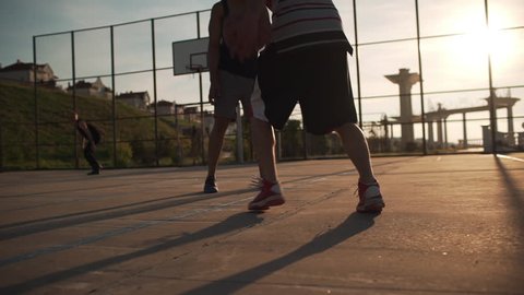 Group of Caucasian males playing streetball dribbling passing having fun. Footage in slowmotion with sun flare