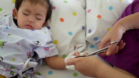 A skilled pediatric nurse removing an intravenous (IV) line on the baby patient's hand, getting the baby ready to go back home