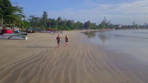 Young couple jogging on the empty beach morning time drone footage