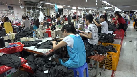 HCMC, VIETNAM - DECEMBER 2015: Men and women work in a clothing factory in Ho Chi Minh City in Vietnam, Southeast Asia