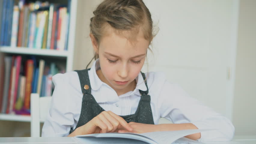 Cute little girl is reading book. Slow motion.