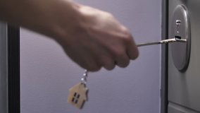 Close-up slow motion shot of female hand holding door keys with wooden house shaped key ring. Woman locking or unlocking door of her house or apartment. - Powered by Shutterstock - Get 15% off with code: PIKWIZARD15