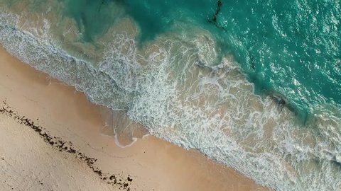 Flying view of the beach line in Cancun Mexico showing the sand and the sea waves interacting along the beach