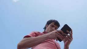 Businessman uses smart phone on a blue sky background. slow motion. 1920x1080