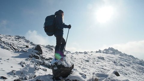 Woman Reaching The Top Of The Snow Mountain. Hiker Tourist Hiking In Mountains In Winter. Girl walking in nature enjoying beautiful mountain landscape nature background enjoying vacation travel