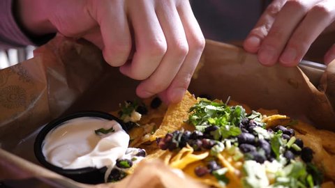 Young man in Mexican cuisine restaurant eating nachos with a sauce