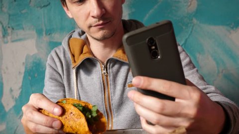 Guy takes phone selfie in Mexican cuisine restaurant during eating tacos
