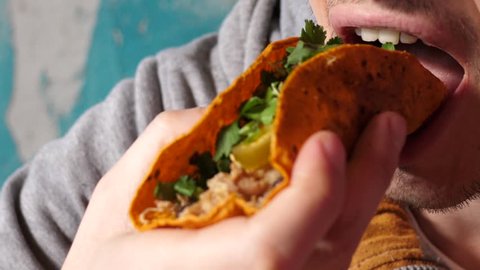 Young man in Mexican cuisine restaurant close up eating tacos