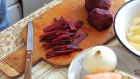Female hands cut the beetroot on a kitchen board with a knife