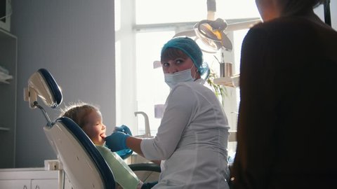 Little girl with mommy in dentist chair - child is playing - Βίντεο στοκ