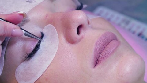 Close up woman face. Eyelash extension procedure. Young woman in a beauty salon