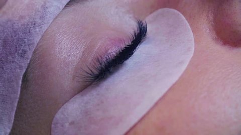 Extreme close up woman eye. Eyelash extension procedure. Young woman in a beauty salon